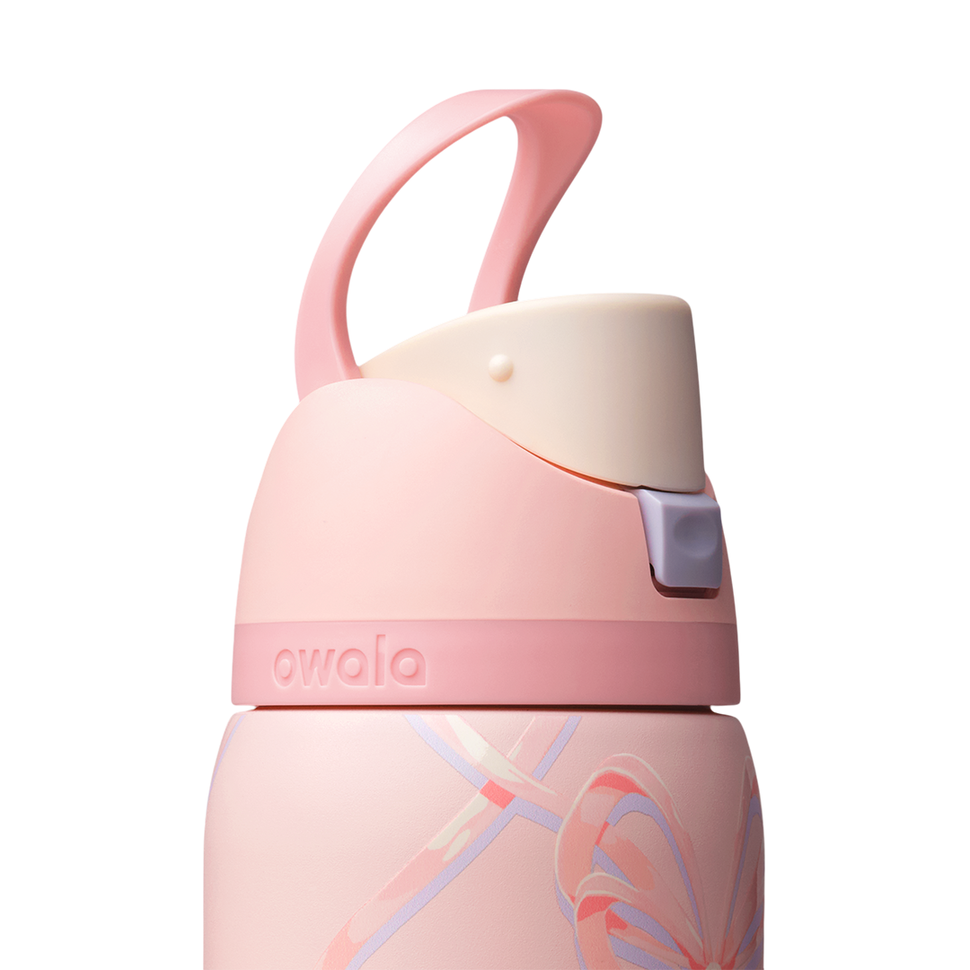 Owala FreeSip 32oz in Sugar Plum Fairy, close-up of pink lid with cream flip cap and pink carry loop raised above the bow-patterned body