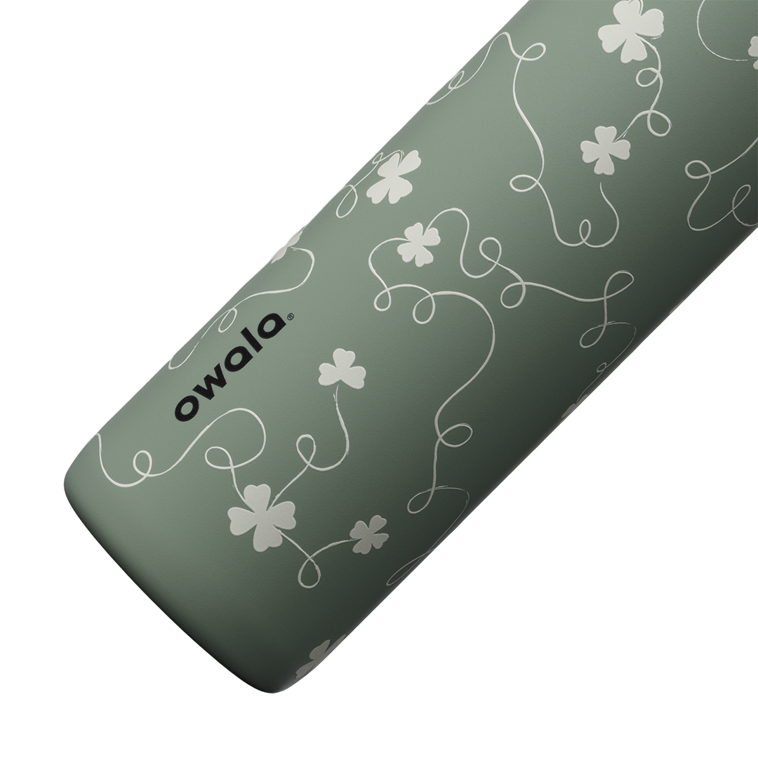 Owala FreeSip Twist 24oz in Clover Achiever, close-up of the sage green body showing the white clover and vine pattern and the Owala logo